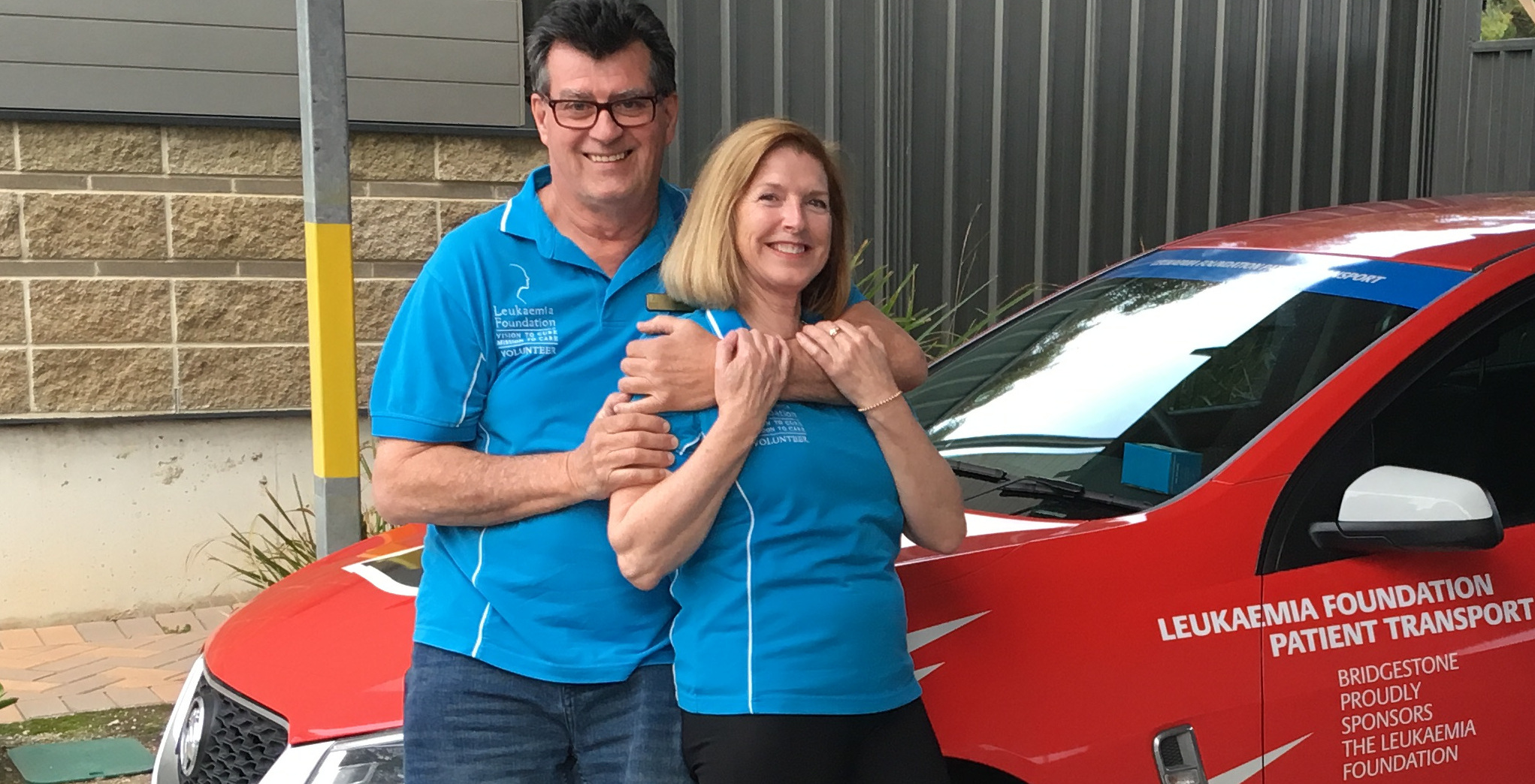 Volunteers Ian and Lyn stand beside a Leukaemia Foundation transport car