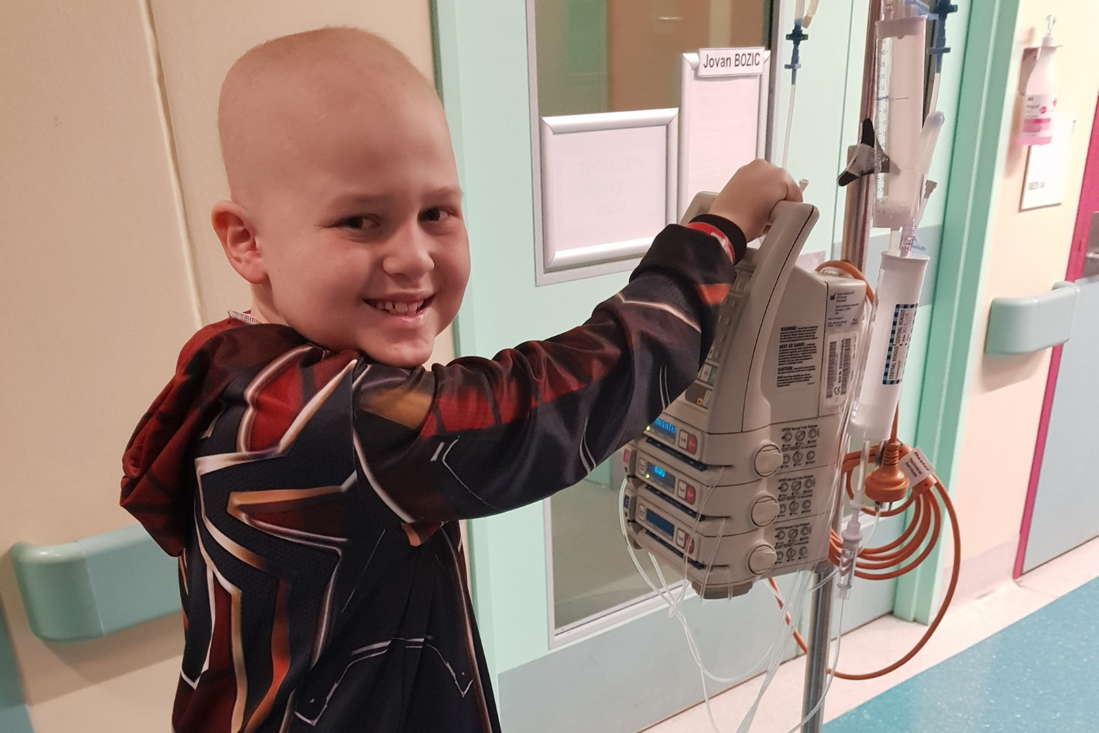 A smiling young boy holding a hospital machine