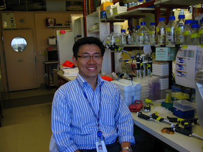 Dr Seong Lin Khaw sits on a chair in a science laboratory