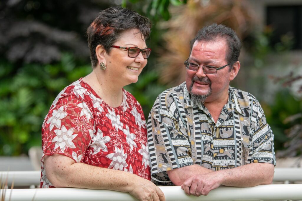 Belinda and John-Michael Barrie stand outside in a garden, smiling